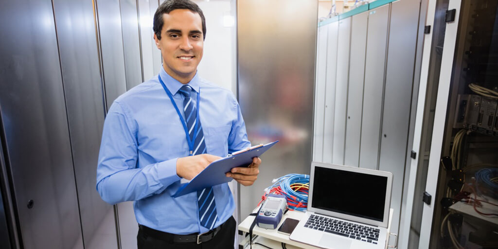 Portrait of happy technician holding clipboard in server room.jpeg